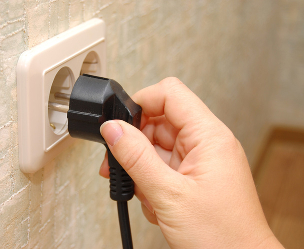 Female hand sticks a plug in the socket - Foto, Imagen