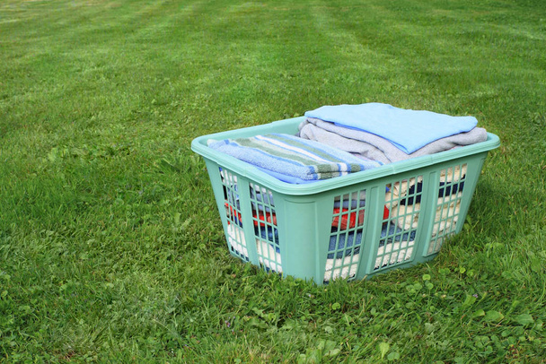 neatly folded laundry in plastic laundry hamper on lawn - Фото, зображення