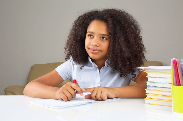 μαύρο σχολείο κορίτσι γράφει σε ένα σημειωματάριο, κάνει την εργασία - Φωτογραφία, εικόνα