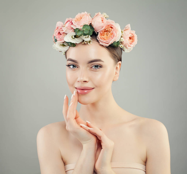 Χαμογελαστή γυναίκα με καθαρό δέρμα. Μοντέλο σπα με λουλούδια - Φωτογραφία, εικόνα