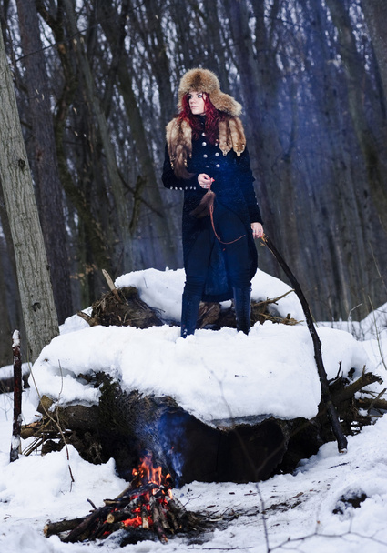 Portrait of red haired beautiful and wild yang woman the hunter in the winter gloomy forest. - Photo, Image