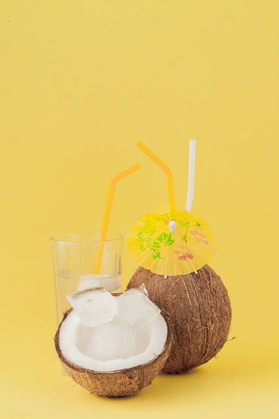 Fresh Coconut cocktail with a straws on yellow background - 写真・画像