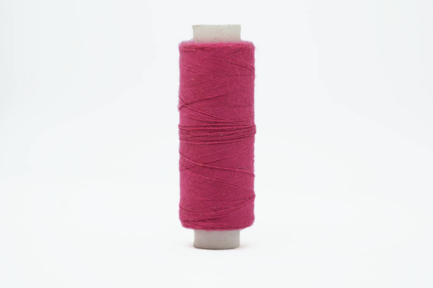 Alargada madeja de plástico de hilo rosa para una máquina de coser de cerca aislada sobre un fondo blanco
. - Foto, Imagen