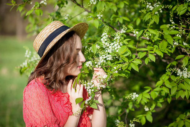 Young girl blowing nose and sneezing in tissue in front of blooming tree. Seasonal allergens affecting people. Beautiful lady has rhinitis. - Фото, зображення