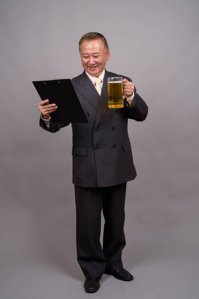 Ritratto di maturo uomo d'affari asiatico su sfondo grigio
 - Foto, immagini