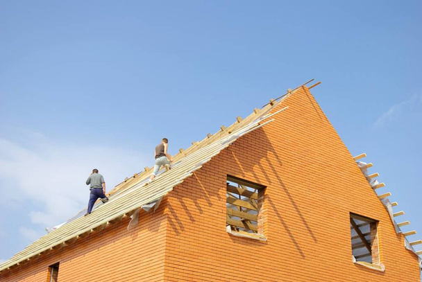 Trabalhadores da construção que colocam a primeira seção do telhado em uma nova casa em construção
. - Foto, Imagem