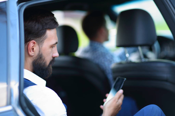 Sulje up.businessman käyttäen älypuhelinta istuessaan autossa
. - Valokuva, kuva