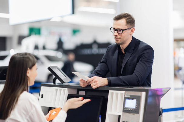 Knappe zakenman overhandigt vliegticket bij check-in balie - Foto, afbeelding