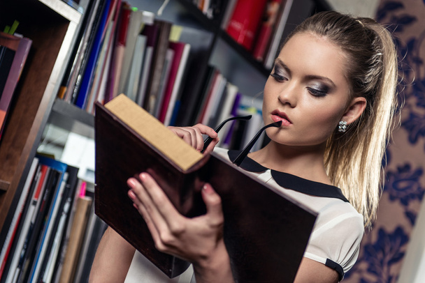 Female student at the library holding a book - Фото, зображення