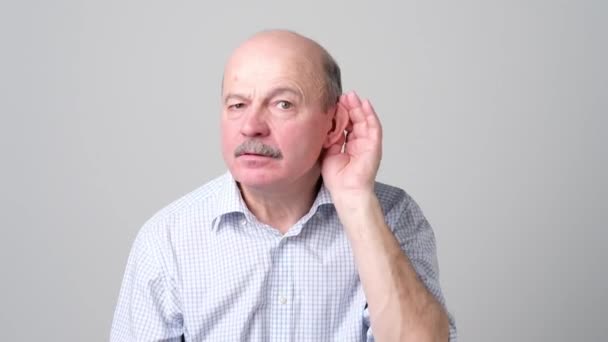 Senior Bald Man luisteren naar roddels over andere met de hand in de buurt van oor. - Video
