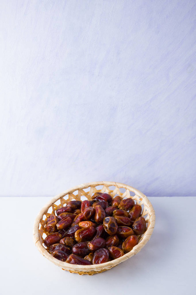 Dried dates on white background. Holy month of Ramadan, concept. Righteous Muslim lifestyle. Starvation. Dates in wooden basket. Vegetarian food. Copy space - Фото, изображение