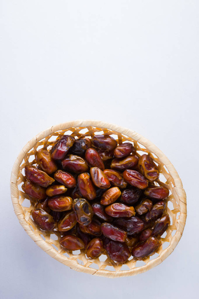 Dried dates on white background. Holy month of Ramadan, concept. Righteous Muslim lifestyle. Starvation. Dates in wooden basket. Vegetarian food. Copy space - Foto, Bild