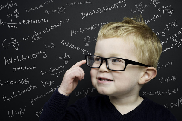 Smart young boy stood infront of a blackboard - 写真・画像