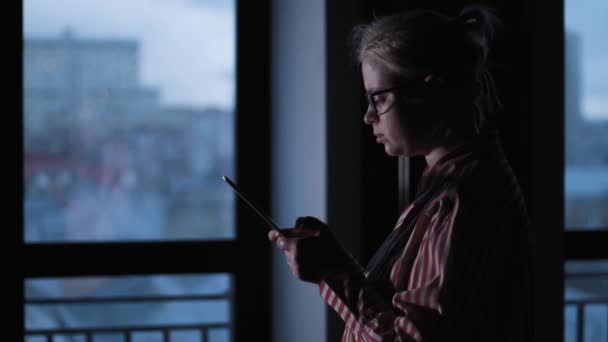 Beatiful dziewczyna używa cyfrowego tabletu przed snem. Dziewczyna używa tabletu. Izolowane czarne. Widok z przodu - Materiał filmowy, wideo