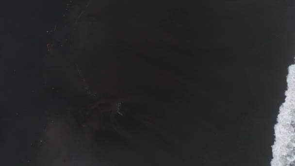 Draufsicht Luftbild von der fliegenden Drohne von erstaunlicher Natur Blick auf vulkanischen schwarzen Sandstrand und schöne Wellen des Indischen Ozeans. Perfekter Hintergrund für eine Webseite mit Kopierplatz für Ihren Text - Filmmaterial, Video