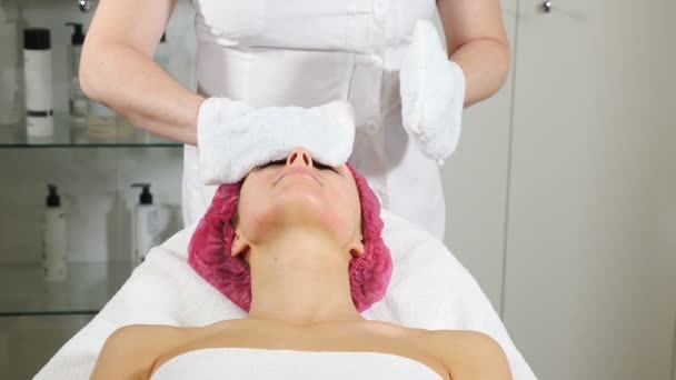 Kosmetikerin wischt Gesicht nach Schönheitsmaske von Kundin ab Nahaufnahme. Frau bekommt Hautbehandlung in modernen Salon. hd - Filmmaterial, Video