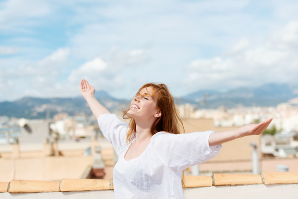 Woman on a rooftop embracing the sunshine - Valokuva, kuva