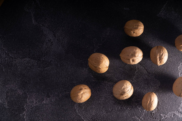 Bunch of whole walnuts on dark blue slate background. Healthy diet composition. - Foto, imagen