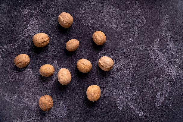 Bunch of whole walnuts on dark blue slate background. Healthy diet composition. - Фото, изображение