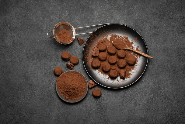 Chocolate truffles candies and cocoa powder on dark concrete background - Photo, Image