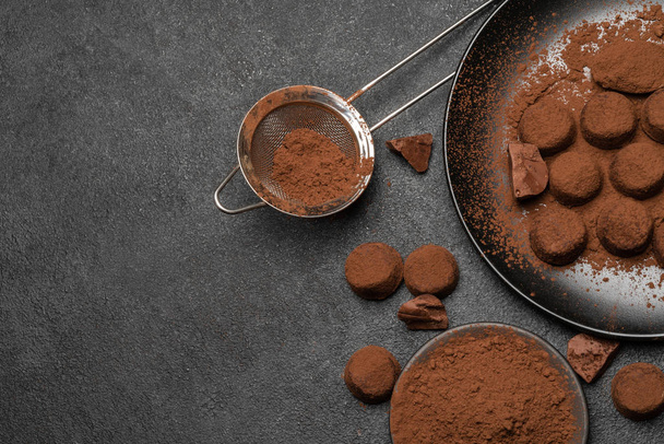 Chocolate truffles candies and cocoa powder on dark concrete background - Foto, Imagem