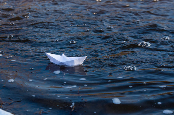 A paper boat on a turbulent stream of water struggles with the flow. Small paper boat is flowing along river. - Fotografie, Obrázek