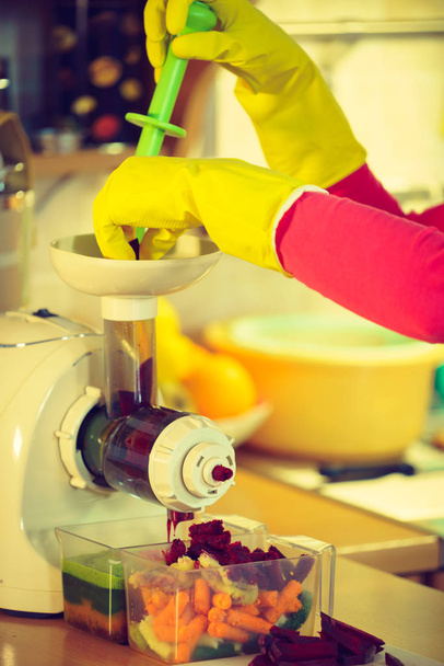Woman make vegetables juice in juicer machine - Valokuva, kuva