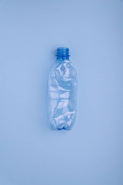 Bater garrafa de plástico no fundo azul brilhante. Conceito de utilização de plástico. Problema ecológico, ambiente global
. - Foto, Imagem
