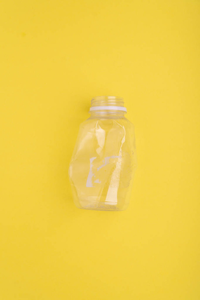 Crashed plastic bottle on yellow background. Plastic utilisation concept. Ecological problem, global environment. - Foto, Imagen
