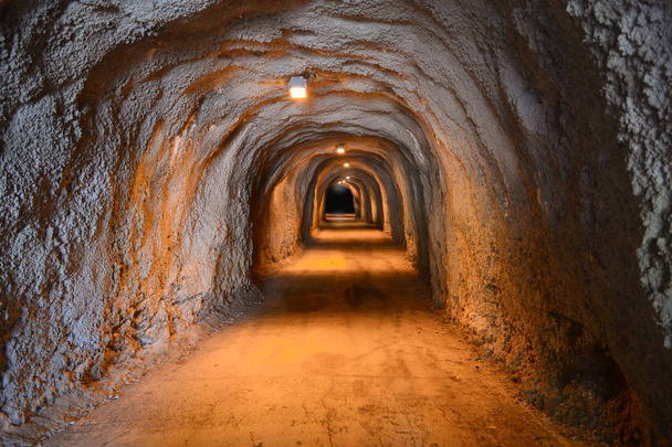 ein alter beleuchteter unterirdischer Tunnel, der sich bis in die Dunkelheit erstreckt. - Foto, Bild