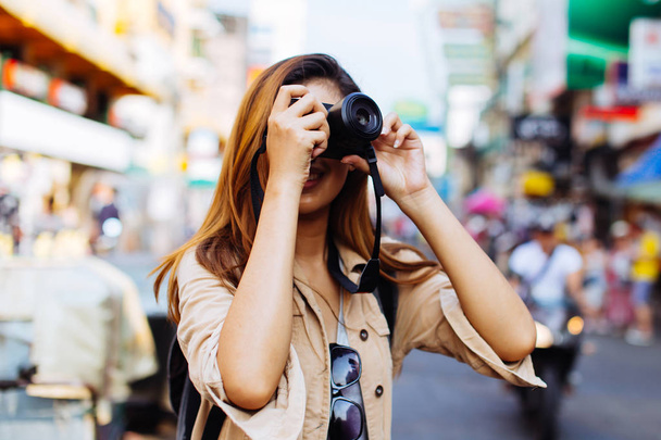 Young woman holding a camera and taking photos in Thailand - Fotó, kép