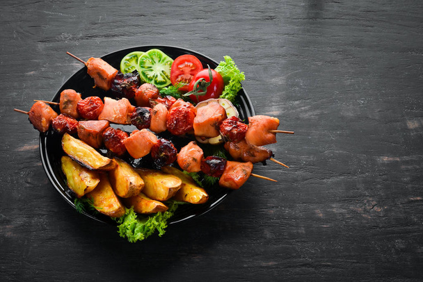 Chicken shish kebab with potatoes and vegetables on a black background. Meat. Top view. Free copy space. - Foto, Imagem