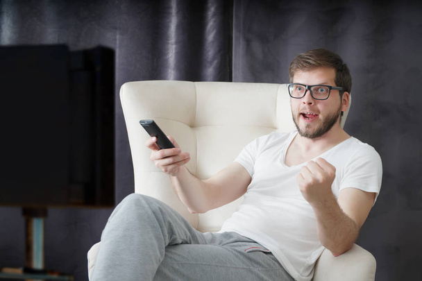 man holding remote control and watching football on TV - Photo, Image