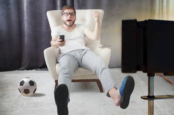 homem segurando controle remoto e assistir futebol na TV
 - Foto, Imagem