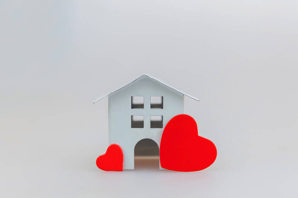 Diseño simplemente minimalista con casa de juguete blanco en miniatura con corazón rojo aislado sobre fondo blanco
 - Foto, Imagen