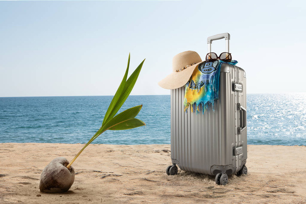 view of  suitcase with hat, pareo and sunglasses on sunny tropic beach - Photo, Image