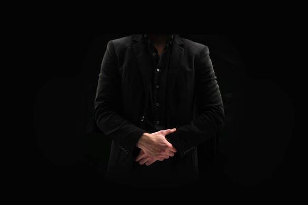 Portrait of a business man in a dark suit and unbuttoned shirt on a black background. Male does not show face. Without face - Photo, Image