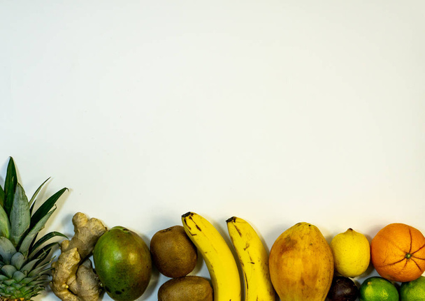フルーツのセット、下部にフルーツと写真の上部にフリースペース、白い背景、パイナップルオレンジ、バナナ、ライム、キウイ、マンゴー、レモン、パパイヤ、シンダー - 写真・画像
