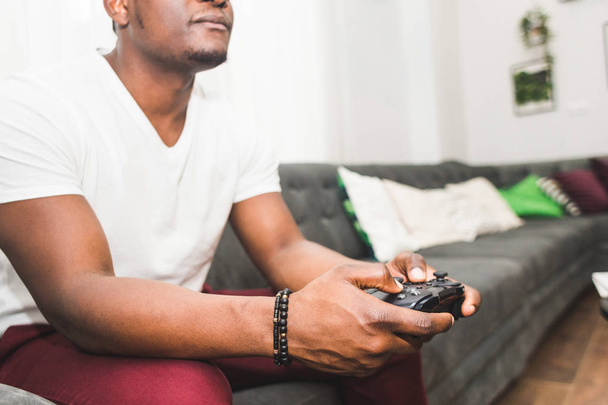Young African American man playing a game console at home. - Foto, Bild