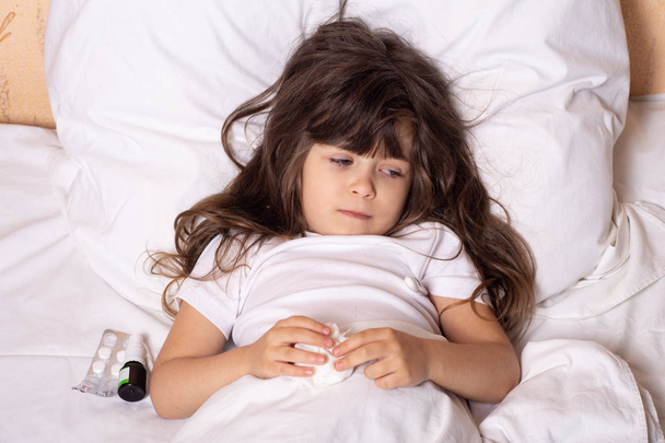 Sairas lapsi, jolla on kuume ja sairaus sängyssä, tarkistaa lämpötilan lämpömittarilla. Lapset saavat flunssahoitoa. Vakuutuskäsite
. - Valokuva, kuva