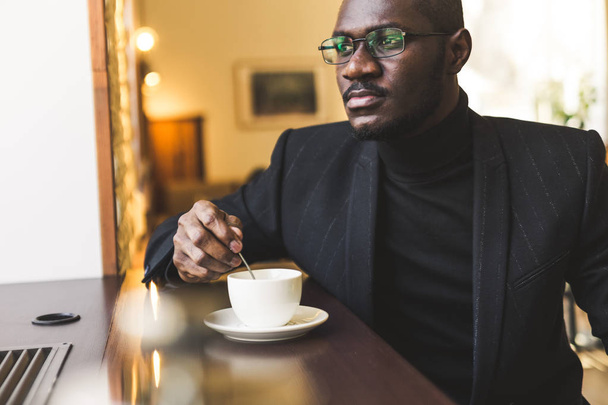 Jovem bonito empresário de pele escura em um café com uma xícara de chá
. - Foto, Imagem