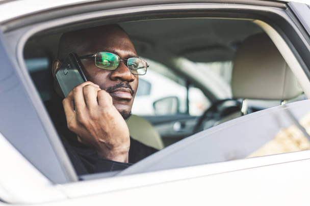 Nuori menestynyt liikemies puhuu puhelimessa istuen kalliin auton takapenkillä. Neuvottelut ja liiketapaamiset
. - Valokuva, kuva