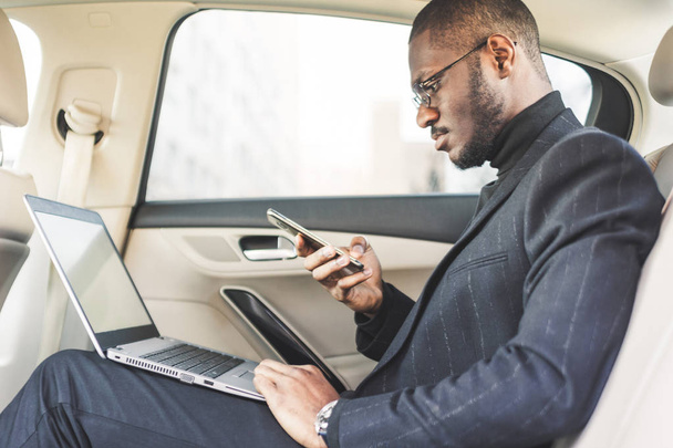 Man in a business suit write on laptop in the salon of an expensive car with leather interior. - Foto, Imagem