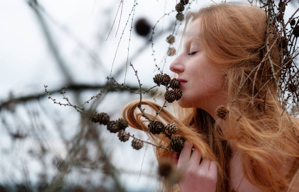 hermosa joven sexy pelirroja chica disfruta sonriendo a los pinos y su hermoso hermoso pelo rojo atrapando en una ramita de pino
 - Foto, imagen