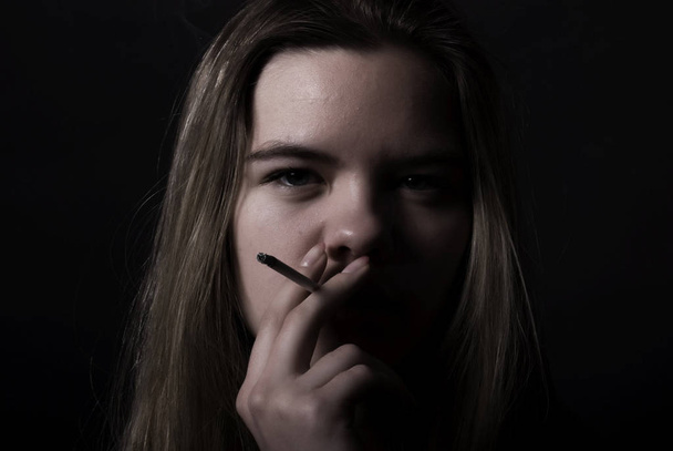 young female  smoking addict over black - Foto, Imagen