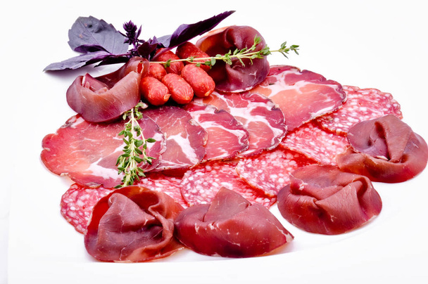 Assorted different kinds of meat and sausages with herbs and basil - Foto, Imagen