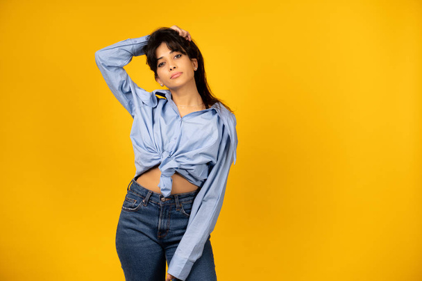Young beautiful girl in a blue shirt posing for a photo on a yellow background. - Foto, Bild
