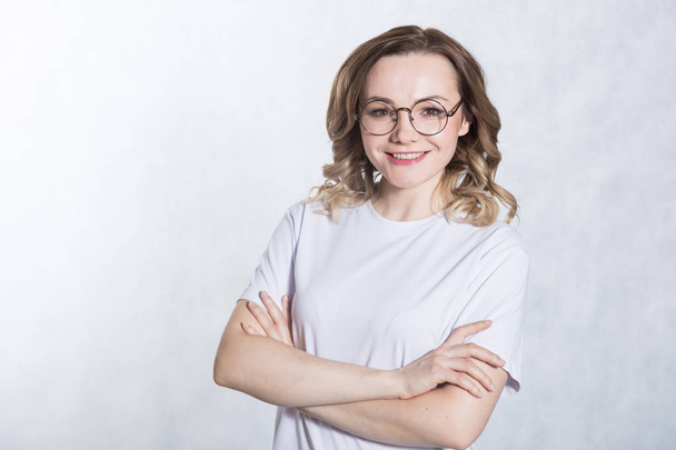 Portrait of a young smiling woman with glasses on a white background. - 写真・画像