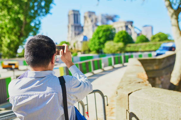 Tourist taking photos of Notre Dame cathedral without roof and spire - Φωτογραφία, εικόνα