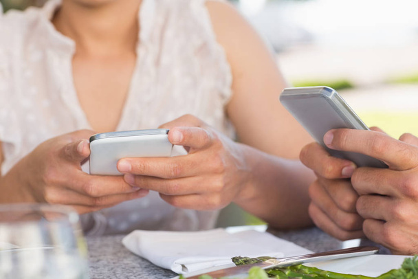 Couple on a date sending text messages in patio of restaurant - Fotó, kép